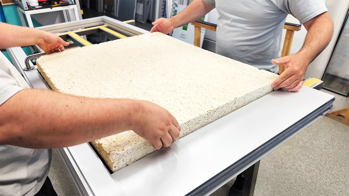 Technicians position a foam core into an aluminum panel frame