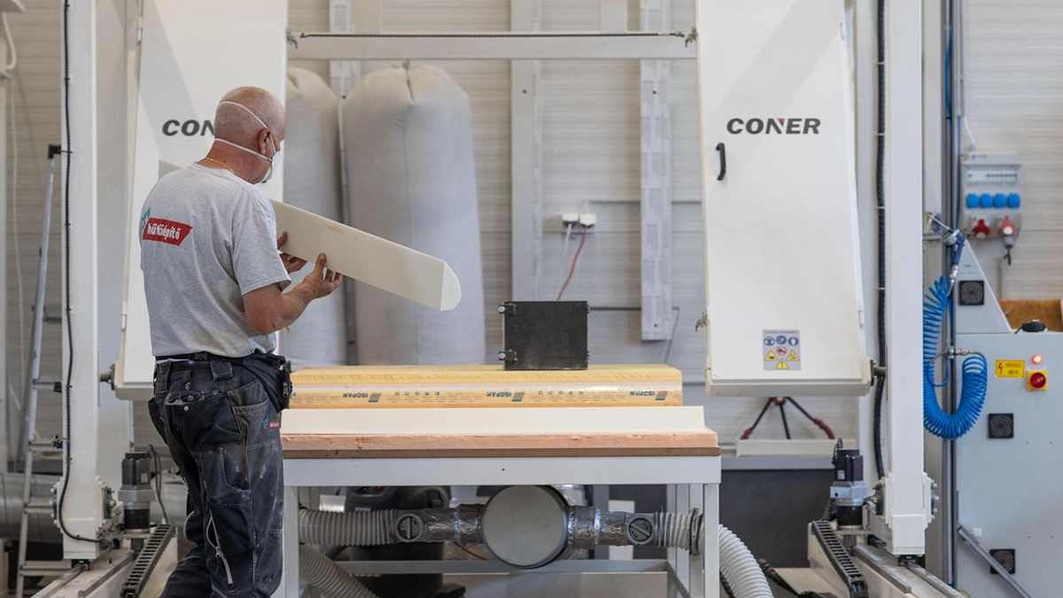 Worker inspects a cut foam piece at a workstation